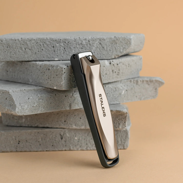 Coupe-ongles Staleks en acier inoxydable posé sur blocs de pierre, accessoire professionnel de manucure.