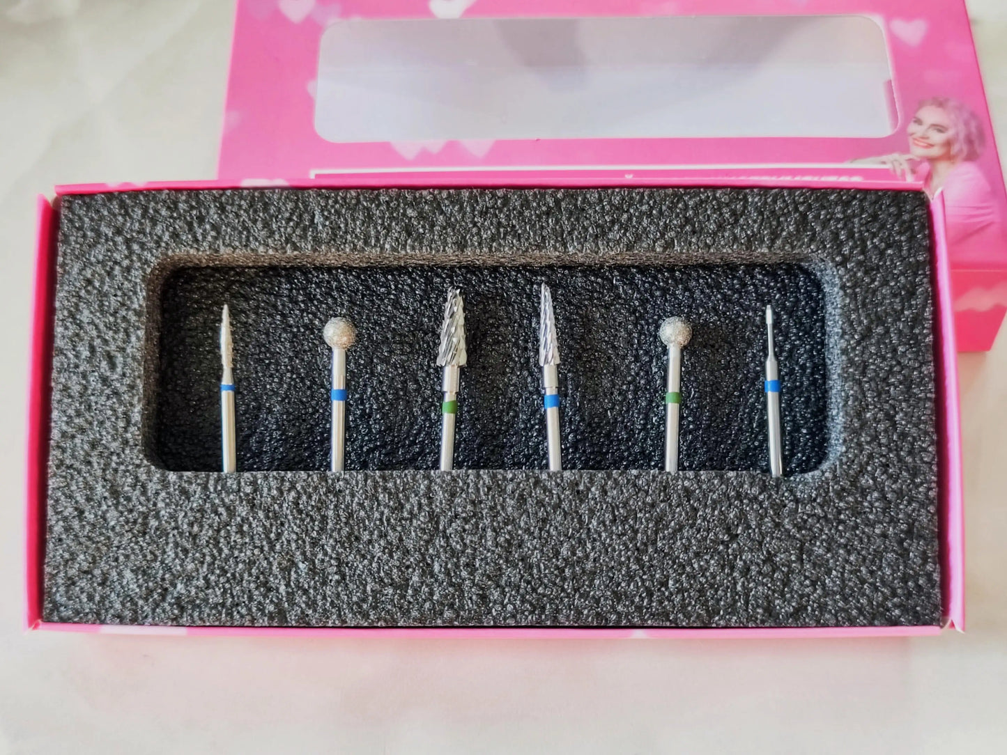 Kit de 6 embouts pour ponceuse à ongles présenté dans une boîte rose avec mousse de protection, idéal pour la manucure professionnelle.